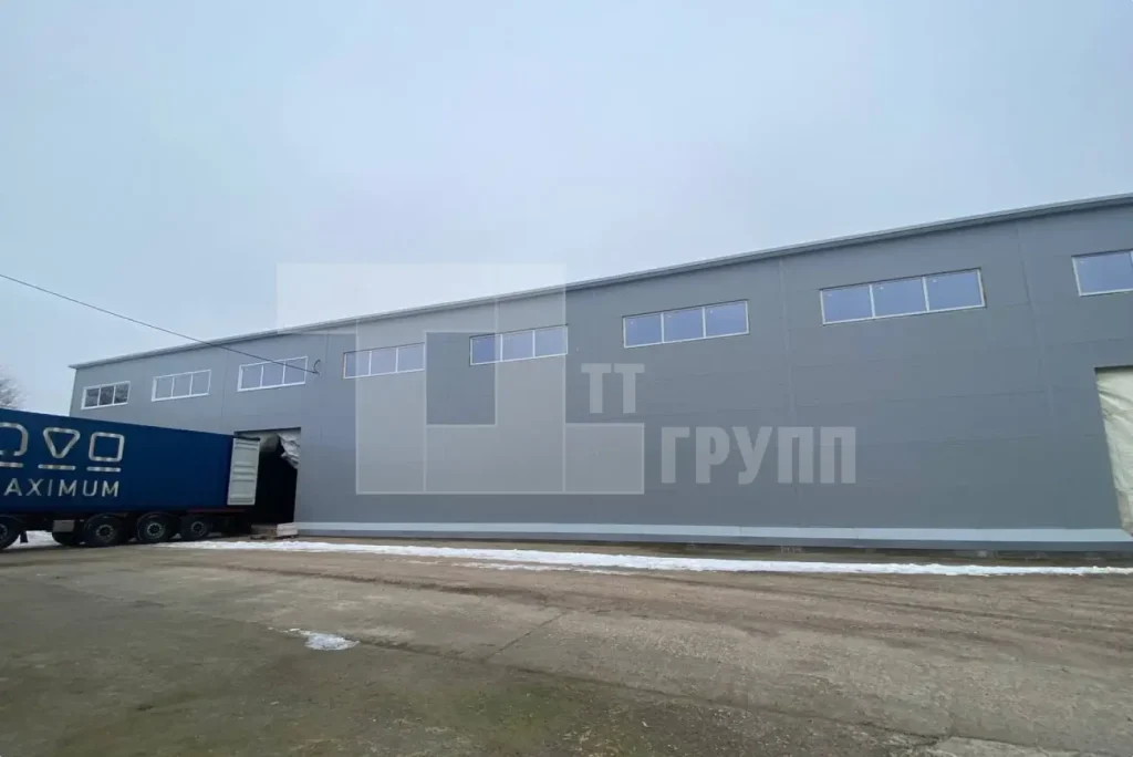Готовый складской корпус снаружи: серые сэндвич-панели, фура у ворот на погрузке