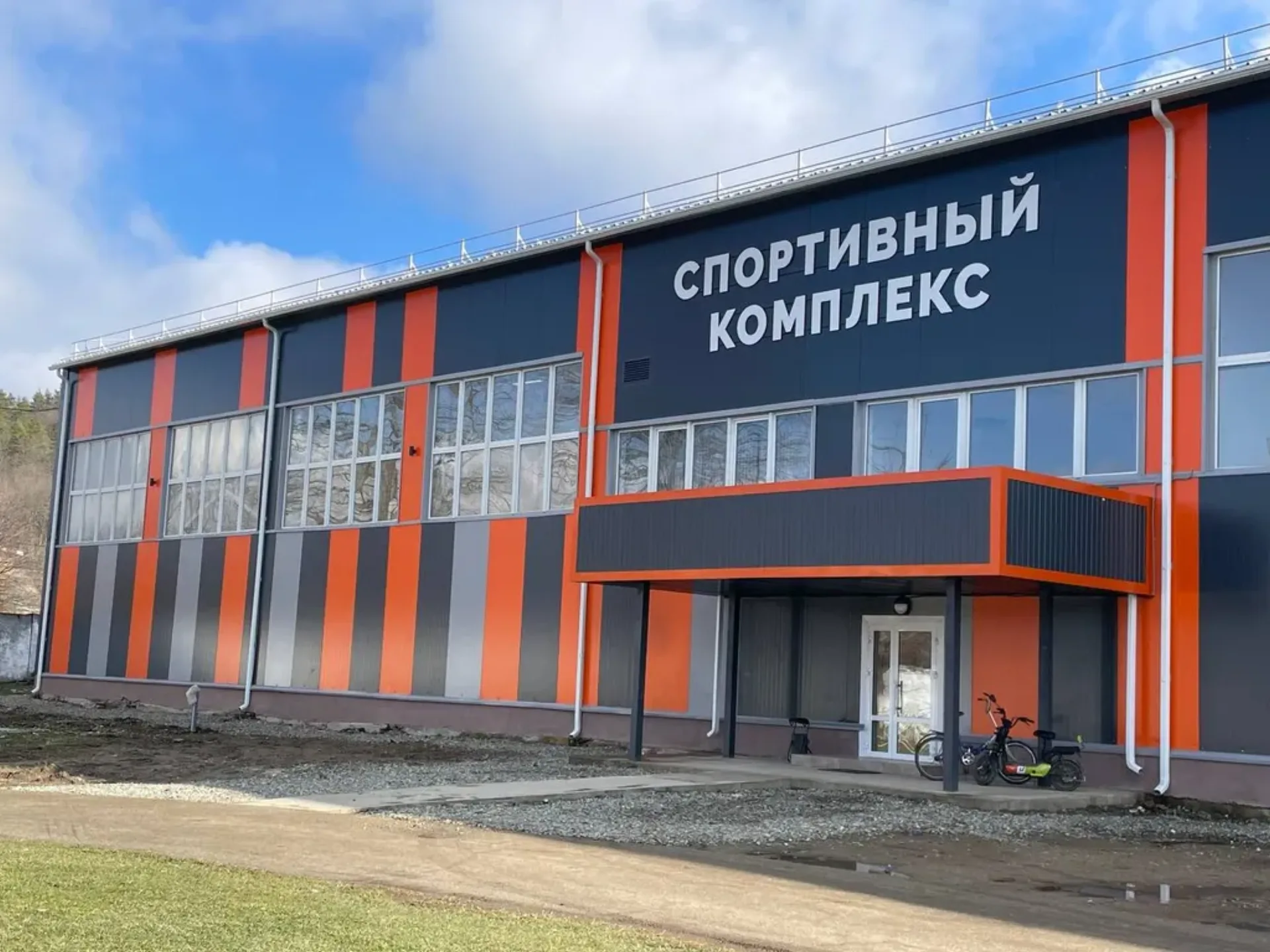 Фасад из сэндвич-панелей в нестандартной для типового склада цветовой схеме: серые, оранжевые и тёмные вертикальные полосы